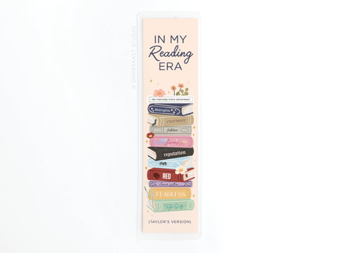 The Onderkast Studio TS In My Reading Era Laminated Bookmark features “IN MY Reading ERA” and a colorful stack of books styled as Taylor Swift album spines, showcasing vibrant print quality.