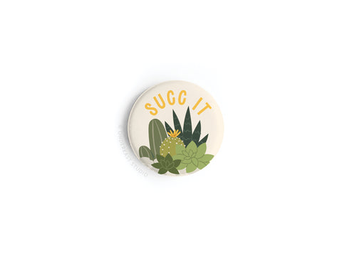 The Succ It Succulents Button Magnet by Onderkast Studio features green succulents and cacti with SUCC IT on an off-white background—perfect as a quirky gift for plant lovers.