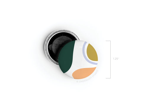 The Abstract No. 1 Button Magnet by Onderkast Studio, now discontinued, features a vibrant green, mustard, orange, and white abstract design. Shown next to its metal backing, it measures 1.25 inches in height.