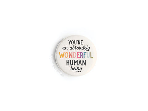 The Onderkast Studio Absolutely Wonderful Human Being Button Magnet features the words Youre an absolutely wonderful human being in vibrant colors on a white background. Proudly printed in the USA.