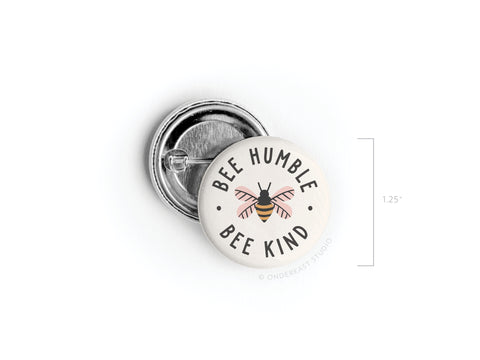 The Bee Humble Bee Kind Pinback Button by Onderkast Studio features a whimsical bee design with the phrase Bee Humble Bee Kind on a white background and measures 1.25 inches in diameter.