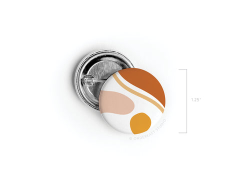 The Abstract No. 5 Pinback Button by Onderkast Studio is a discontinued 1.25 round pin featuring a vibrant abstract design in orange, brown, beige, and yellow on white, shown front and back with a quality pin enclosure.