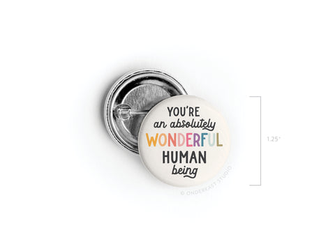 The Onderkast Studio Absolutely Wonderful Human Being Pinback Button features You’re an Absolutely Wonderful Human Being in black, orange, yellow, and pink text and comes in a 1.25-inch size.