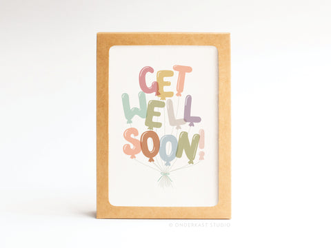 The Onderkast Studio Get Well Soon Balloons Folded Greeting Note Set of 10 features pastel balloon-shaped letters spelling “Get Well Soon!” and each card is framed in a brown cardboard holder for a premium, vibrant look.