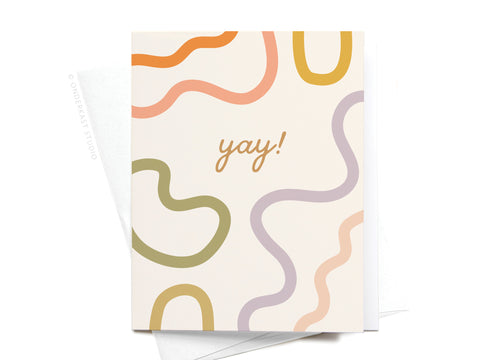The Yay Squiggles Greeting Card by Onderkast Studio features “yay!” in cursive, accented by abstract wavy lines in orange, yellow, green, and lavender on a white background. A matching envelope peeks out underneath for a premium feel.