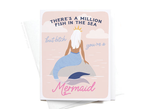 Onderkast Studio’s There’s a Million Fish in the Sea Mermaid Greeting Card features a vibrant mermaid with long white hair, a crown, and blue tail. Front text: Theres a million fish in the sea, but bitch youre a mermaid.