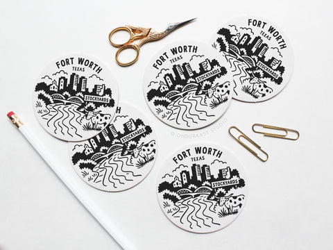 The Fort Worth Texas Skyline Letterpress Coaster Set by Onderkast Studio is displayed on a white surface with gold scissors, paperclips, and a pencil—ideal inspiration for your next creative project.