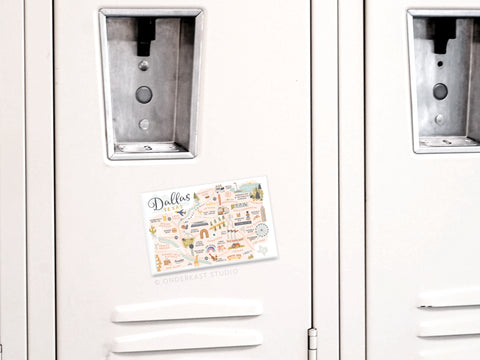 The Dallas Map Refrigerator Magnet by Onderkast Studio, featuring a colorful illustrated design, is displayed on a closed light gray locker door with two similar lockers visible beside it.