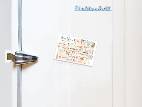 A white fridge door features the Dallas Map Refrigerator Magnet by Onderkast Studio—an illustrated postcard capturing Dallass energy—with a metallic handle. Elektrobrik in blue appears at the top right.