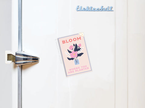 The Bloom Where You Are Planted Refrigerator Magnet by Onderkast Studio features pastel pink, floral art, and an inspirational message, displayed on a vintage white fridge with a latch handle and Elektrobit label.