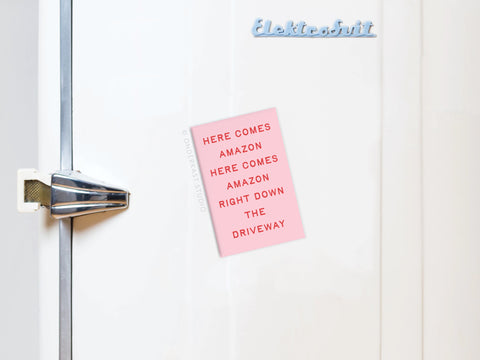 A pink note on a white fridge reads: HERE COMES AMAZON RIGHT DOWN THE DRIVEWAY in red letters. With Elektrosvit at the top, the Onderkast Studio Here Comes Amazon Refrigerator Magnet is perfect for funny holiday shopping reminders.