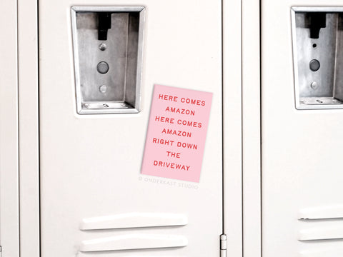 A pink “Here Comes Amazon” magnet from Onderkast Studio adds holiday humor to metal lockers with built-in combo locks—perfect for hallway decor and festive shopping vibes.