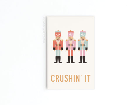 The Crushin’ It Nutcrackers Refrigerator Magnet by Onderkast Studio features three pastel nutcrackers and the words CRUSHIN’ IT in bold letters—a fun, festive addition to your holiday decor.