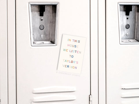 A white locker displays the Onderkast Studio Taylor’s Version Refrigerator Magnet, featuring pastel text: “IN THIS HOUSE WE LISTEN TO TAYLOR’S VERSION”—a perfect accessory for dedicated Swifties. Adjacent white lockers are visible behind.
