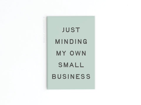 The Just Minding My Own Small Business Refrigerator Magnet by Onderkast Studio features black text on mint green—ideal for entrepreneurs and business owners. Displayed on a plain white background.