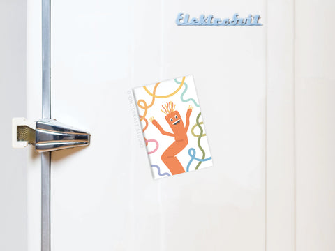 A white fridge with an Onderkast Studio Wacky Waving Inflatable Tube Man Refrigerator Magnet, featuring a playful orange tube man surrounded by colorful squiggly lines.
