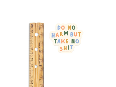 A wooden ruler lies next to the Onderkast Studio Do No Harm But Take No Shit Sticker, a bold weatherproof vinyl sticker about 3 inches wide, shown on a white background.