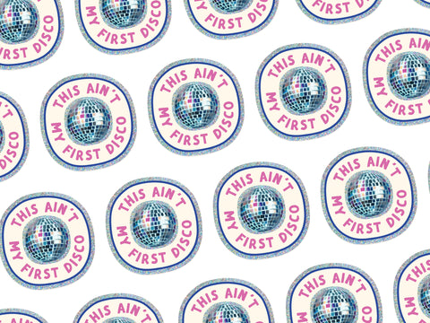 The This Ain’t My First Disco Glitter Sticker by Onderkast Studio features a weatherproof vinyl design with pink This Ain’t My First Disco text and a disco ball, all on a white background for dazzling style.