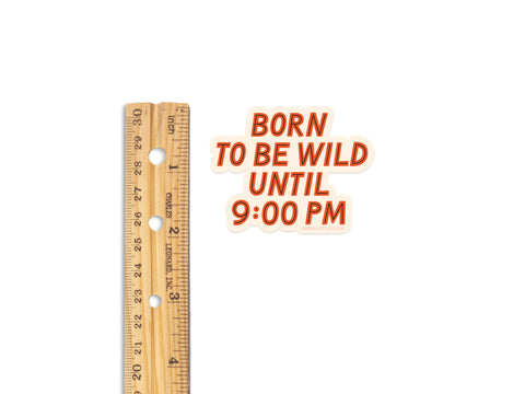 A wooden ruler stands upright next to an Onderkast Studio Born To Be Wild Sticker, made of weatherproof vinyl with bold orange letters on a white background.