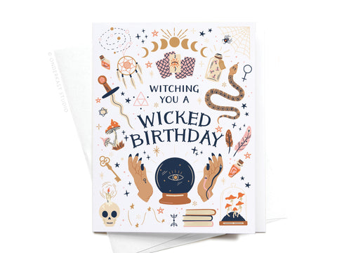 The Witching You a Wicked Birthday Greeting Card by Onderkast Studio features mystical illustrations—crystal ball, potions, stars, skull, and snake—and the front message “Witching You a Wicked Birthday.” Perfect for lovers of magical vibes.