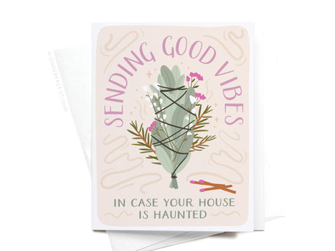The Sending Good Vibes Smudge Stick Greeting Card by Onderkast Studio features a sage bundle with flowers, two illustrated matches, “Sending Good Vibes” surrounding it, and “In case your house is haunted” at the bottom.