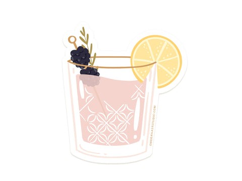 The Berry Cocktail Sticker by Onderkast Studio shows a pink drink with a lemon slice and two blackberries on a pick, set in a water-resistant glass wrapped in a stylish, durable vinyl sticker.