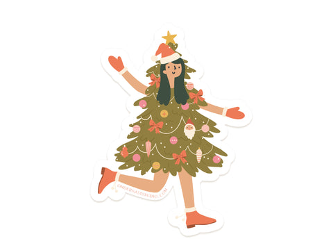 Christmas Tree Girl Sticker by Onderkast Studio features a playful person dressed as a tree with ornaments, bows, star topper, Santa hat, red gloves, and boots—printed on durable vinyl.