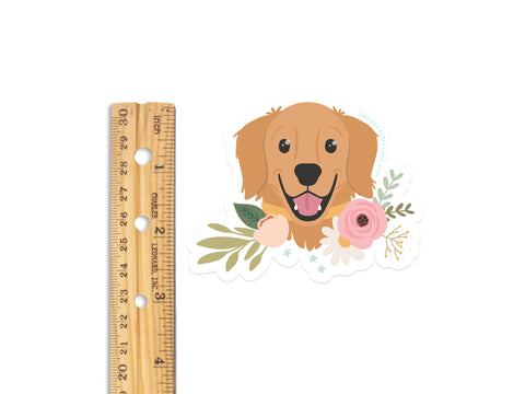 The Golden Retriever Floral Sticker by Onderkast Studio features a smiling golden retriever with flowers, measures about 3 inches wide, and is made from water-resistant, durable vinyl with a white background.