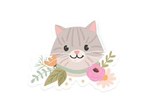 The Tabby Cat Floral Sticker by Onderkast Studio features a smiling gray tabby cat with pink cheeks, surrounded by colorful flowers and green leaves. Made from durable, water-resistant vinyl with a white background—perfect for any surface.