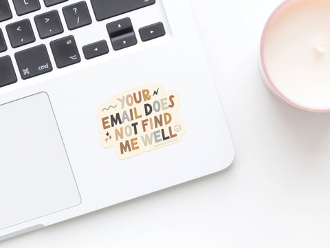 The Your Email Does Not Find Me Well Sticker by Onderkast Studio sits on a laptop keyboard beside a pink candle—a true burnout badge, printed in the USA.
