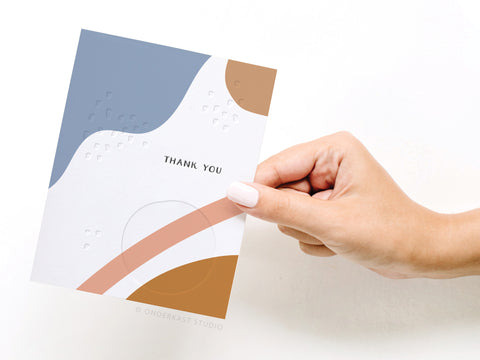 a hand holding a thank you card with a design on it