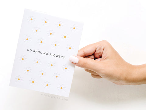 a hand holding a card that says no rain, no flowers