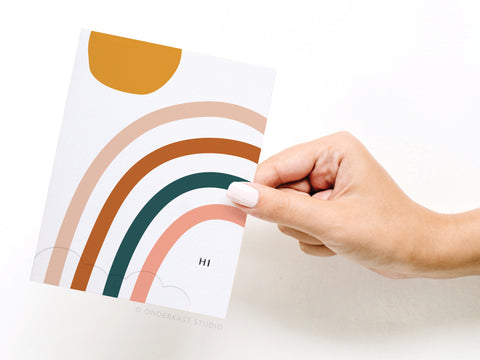 a person holding a card with a rainbow design on it